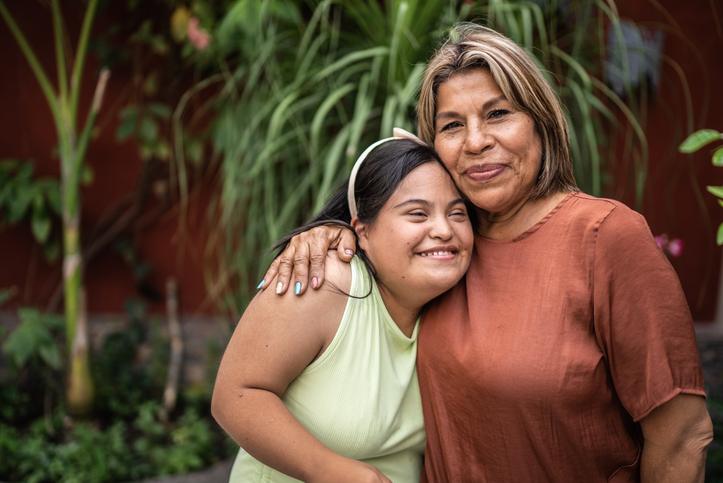 Portrait of mother embracing her daughter with special needs outdoors