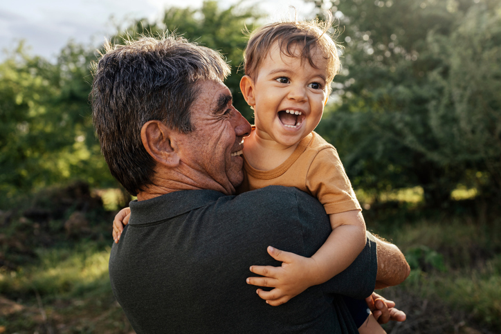 Playful grandfather spending time with his grandson in park on sunny day