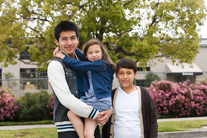 Three latino siblings standing outdoors, portrait