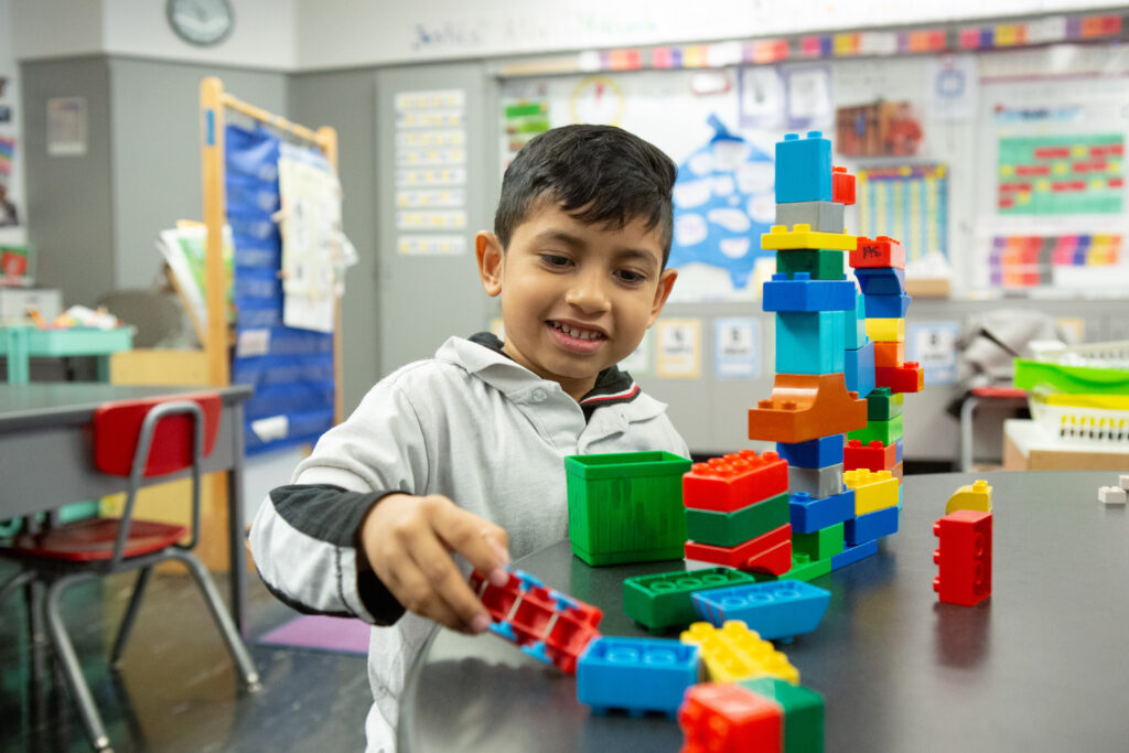 A preschool student builds with stacking bricks during a center rotation.