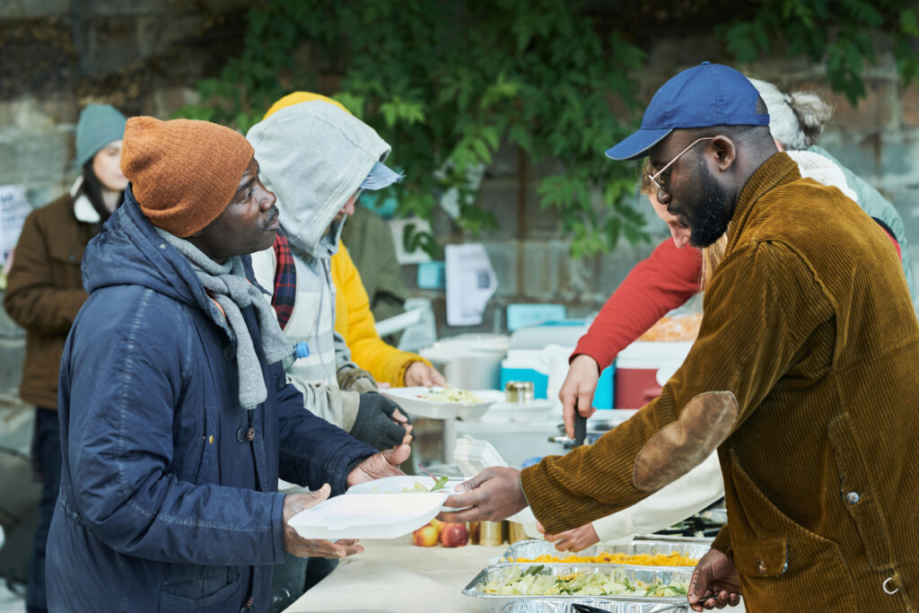 Volunteers sharing food, they putting hot meal on people's plates