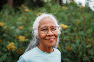 Portrait of an active senior woman of Hawaiian and Chinese descent smiling directly at the camera with a look of gratitude while on a beautiful nature hike to view wildflowers.