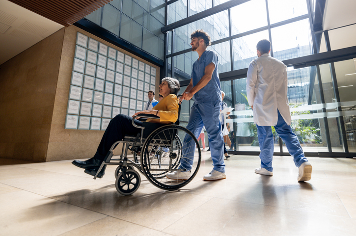 Latin American nurse pushing a senior woman in a wheelchair at the hospital - assisted living concepts