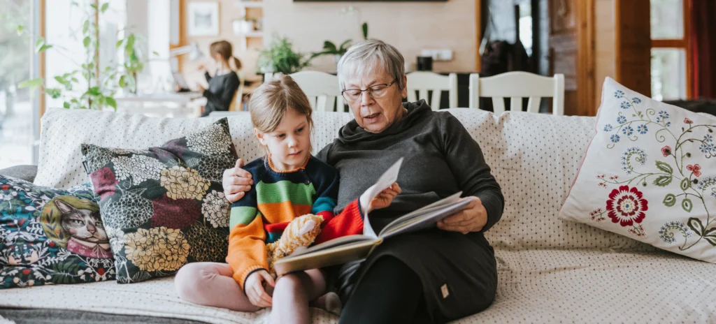 An elderly woman reads a book to a young child.