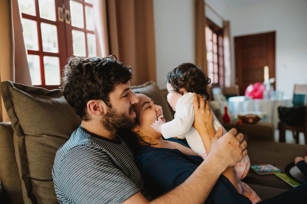 Father and mother playing with toddler on the sofa